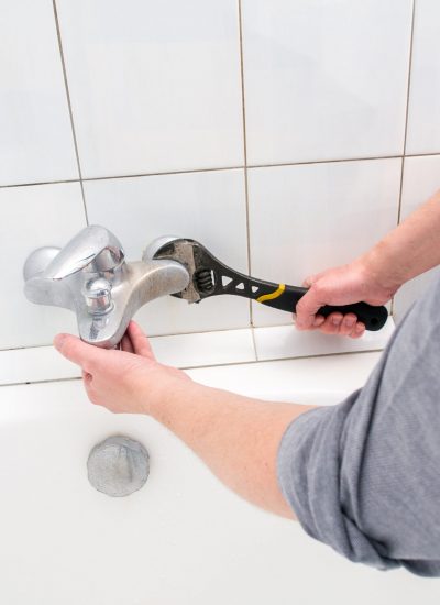 Plumber uninstalling water faucet in the bathroom